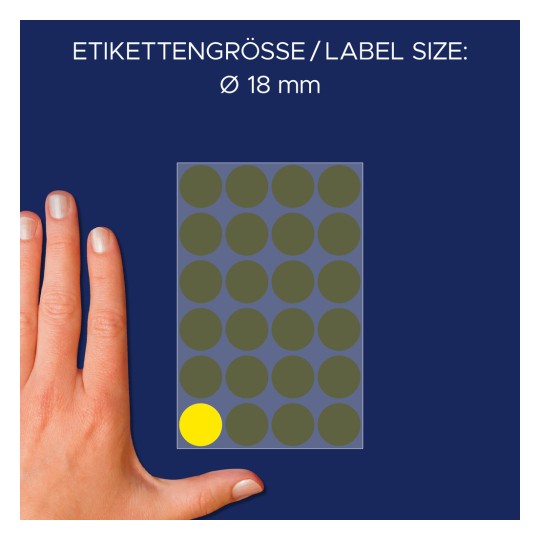 Kuva näyttää käden pyöreiden etikettien arkin vieressä. Tarrat ovat enimmäkseen tummanvihreitä, ja yksi tarra on korostettu keltaisella. Tarrakoko on Ø 18 mm.