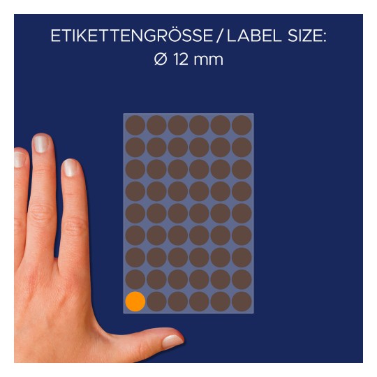 Kuva esittää kättä tarra-arkin vieressä, jossa tarran koko on 12 mm halkaisijaltaan tummanruskeine ympyröineen ja yksi oranssi ympyrä.