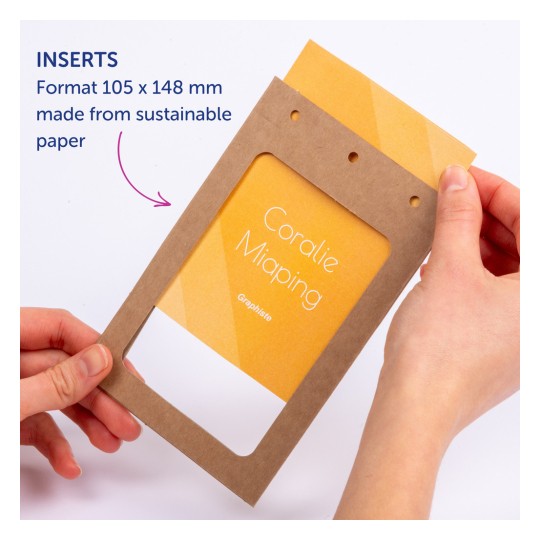Kuvassa henkilö pitelee ruskeaa paperikehystä, jossa on keltainen sisäosa ja nimi 'Coralie Miaping'. Kehyksessä on reikiä ja siihen on merkitty 'Inserts' sekä tietoa sen koosta ja kestävästä materiaalista.