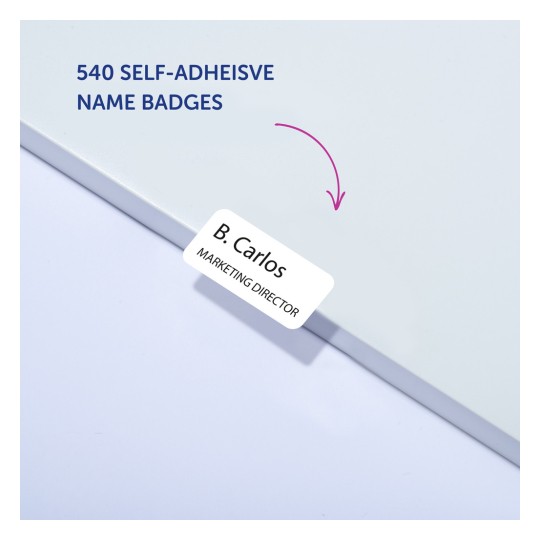 Kuvassa on paketti itseliimautuvia nimilappuja, joissa on teksti '540 SELF-ADHESIVE NAME BADGES' ja nimilappu, jossa lukee 'B. Carlos - MARKKINOINTIPÄÄLLIKKÖ'.