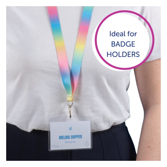 Kuvassa on henkilö, jolla on värikäs nauha ja tunnus, jossa lukee 'Melina Dopper, Suunnittelija.' Nauha vaihtuu vaaleanpunaisesta keltaiseen ja siniseen, ja puhekuplassa lukee 'Ihanteellinen TUNNISTEKORTTIEN PIDIKKEILLE.'