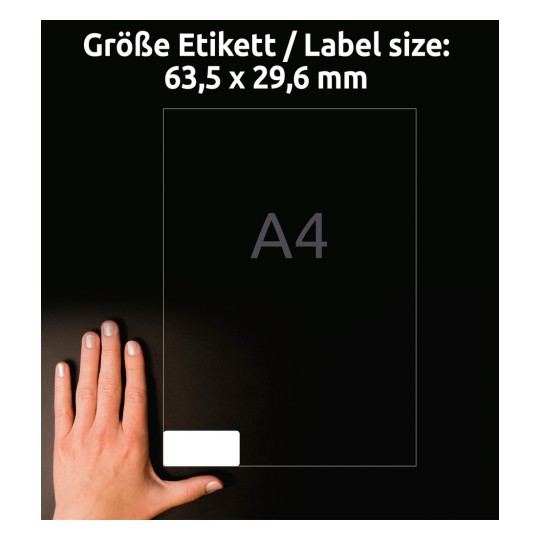 Kuva näyttää käden sijoitettuna läpinäkyvän etiketin viereen. Se osoittaa etiketin koon 63,5 x 29,6 mm ja A4-formaatin taustan.