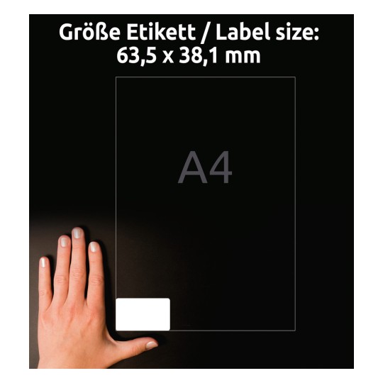 Kuvassa näkyy käsi lepäämässä kokotaulukon vieressä, jonka mitat ovat 63,5 x 38,1 mm ja jossa on A4-merkintä. Tausta on tumma, korostaen etikettiä ja kättä.