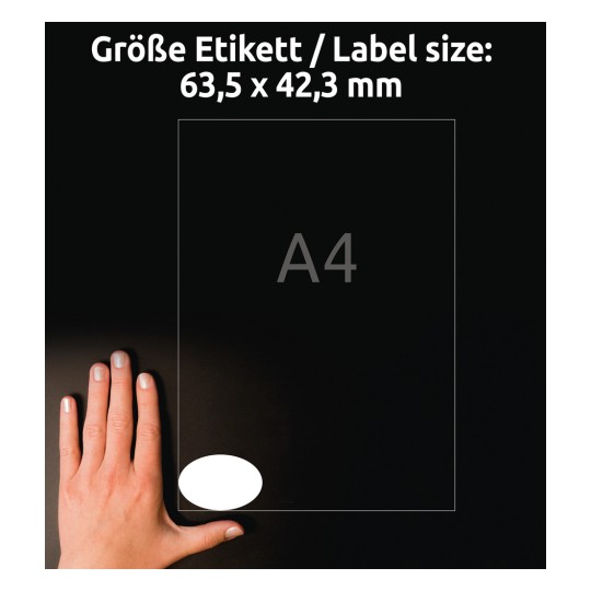 Kuvassa näkyy käsi, joka on sijoitettu etiketin viereen, jonka mitat ovat 63,5 x 42,3 mm, A4-referenssin rinnalla. Tausta on musta.
