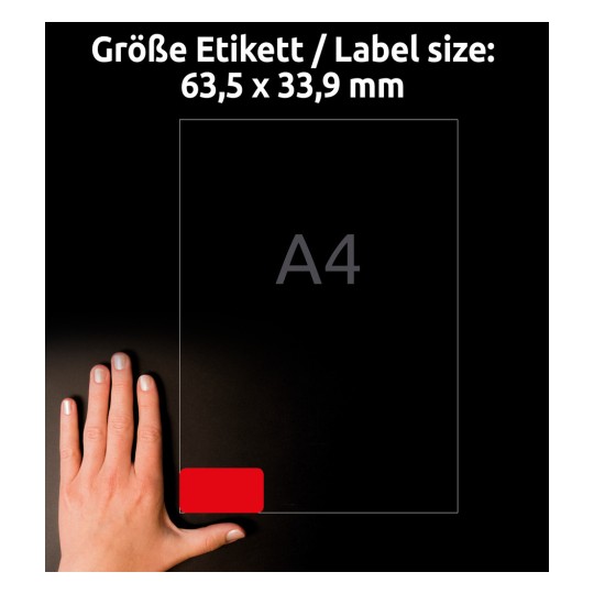 Kuvassa näkyy käsi tarran vieressä tummalla taustalla, mikä osoittaa tarran koon olevan 63,5 x 33,9 mm, viitteenä 'A4'.