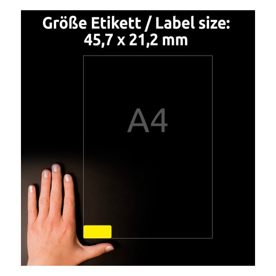 Kuva näyttää käden A4-kokoisen paperin vieressä, jossa on 45,7 x 21,2 mm kokoinen etiketti ja keltainen etiketti alakulmassa.