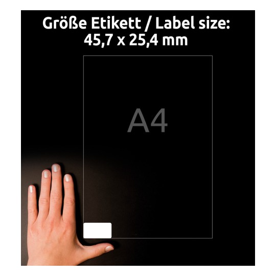 Kuvassa on käsi, joka on asetettu läpinäkyvän arkki 'A4' viereen, ja yläpuolella on mitat 45,7 x 25,4 mm. Tausta on tumma, mikä korostaa etikettiä ja kättä.