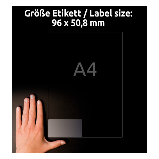 Kuva näyttää käden läpinäkyvän tarran vieressä, jonka mitat ovat 96 x 50,8 mm. Tarra on asetettu mustalle pinnalle, ja teksti 'A4' näkyy selvästi.