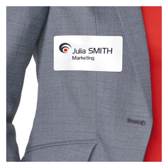 Kuva näyttää henkilön, joka on pukeutunut harmaaseen puvuntakkiin, johon on kiinnitetty nimilappu: "Julia SMITH Marketing".
