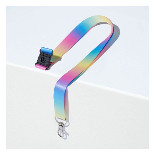 Valkoiselle pinnalle asetettu värikäs liukuvärjätty hihna klipsillä, jossa on sinisen, vaaleanpunaisen ja keltaisen sävyjä.
