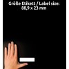 Kuvassa on käsi tyhjän etiketin vieressä mustalla taustalla. Etiketin mitat ovat 88,9 x 23 mm.