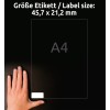 Kuvassa näkyy käsi A4-etiketin vieressä, jonka mitat ovat 45,7 x 21,2 mm. Tausta on tumma, mikä parantaa etiketin ja käden näkyvyyttä.