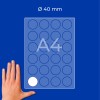 Käsi A4-arkin vieressä, jossa on 40 mm:n pyöreiden tarrojen ruudukko, yksi valkoinen tarra näkyvissä?